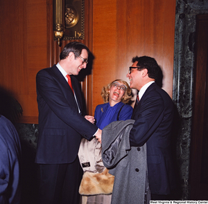 ["Senator John D. (Jay) Rockefeller shakes hands and laughs with an unidentified supporter as an unidentified woman in the background makes a funny face."]%