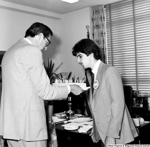 ["Senator John D. (Jay) Rockefeller holds a cake as an unidentified individual from the Presidential Classroom for Young Americans blows out the candles in celebration of West Virginia's birthday."]%