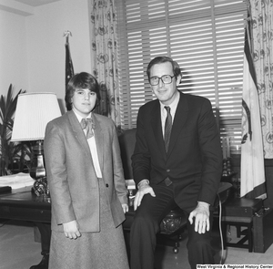 ["Senator John D. (Jay) Rockefeller sits on his desk and poses for a photograph with an unidentified individual."]%