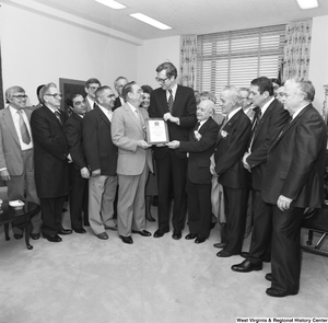 ["Surrounded by a large group in his office, Senator John D. (Jay) Rockefeller accepts an award from the Tin Mill Employees Federal Credit Union."]%