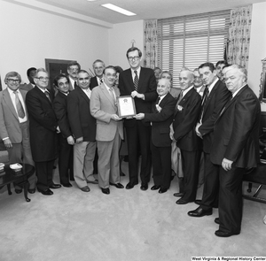 ["Senator John D. (Jay) Rockefeller poses for a photograph with representatives from the Tin Mill Employees Federal Credit Union and the award plaque that they have given him."]%