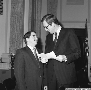 ["Senator John D. (Jay) Rockefeller holds a sheet of paper and talks to an unidentified man in a Senate office."]%