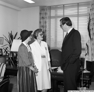 ["Senator John D. (Jay) Rockefeller speaks with two unidentified individuals in his office."]%