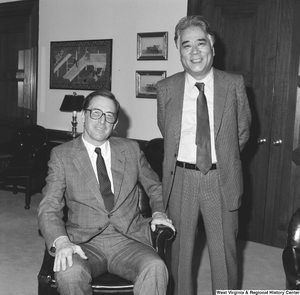 ["Senator John D. (Jay) Rockefeller sits in a chair beside a standing unidentified individual."]%