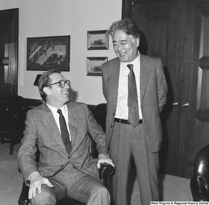 ["Senator John D. (Jay) Rockefeller sits in a chair and laughs with the unidentified man standing next to him."]%