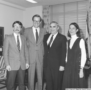 ["Senator John D. (Jay) Rockefeller smiles for a photograph with three unidentified individuals in his office."]%