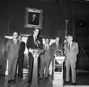 ["Senator John D. (Jay) Rockefeller speaks at a Staggers Rail Reform press event in a Senate building.  Congressmen Nick Rahall and Bob Wise and a man who appears to be Senator Rockefeller's Press Secretary, Timothy Gay, stand behind the Senator."]%