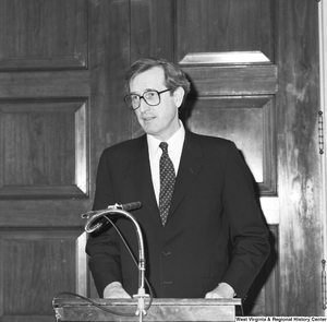 ["Senator John D. (Jay) Rockefeller stands behind a podium and speaks at an unknown event."]%