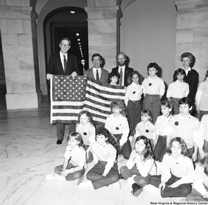 ["This photograph shows a close-up of Senator John D. (Jay) Rockefeller, Congressman Nick Rahall, and a young student holding an American flag during the student group's visit to the Capital."]%