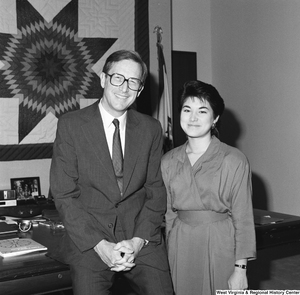 ["Senator John D. (Jay) Rockefeller sits on the corner of the desk in his office  next to an unidentified young woman."]%