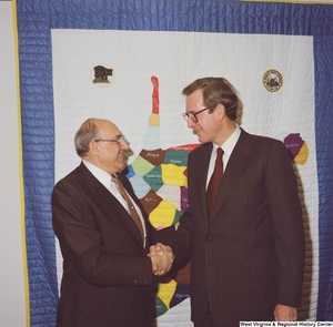 ["Senator John D. (Jay) Rockefeller shakes hands with an unidentified man in his office."]%