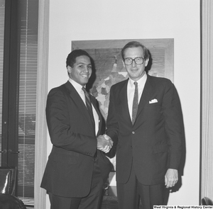 ["Senator John D. (Jay) Rockefeller shakes hands with an unidentified man."]%