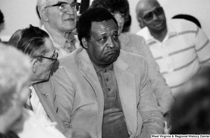 ["An unidentified member of the audience listens as Senator John D. (Jay) Rockefeller speaks."]%