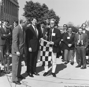 ["Senator Al Gore stands with a trophy at a clean vehicle event outside the Senate."]%