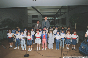 ["Senator John D. (Jay) Rockefeller and Congressman Nick Rahall stand behind a group of kindergartners from Wayne County West Virginia who are dressed in patriotic costumes and appear to be ready to sing a song."]%