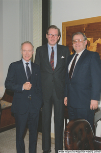 ["Senator John D. (Jay) Rockefeller stands between two unidentified individuals in his office."]%