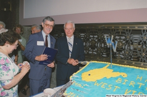 ["Senator Robert C. Byrd cuts a cake that celebrates the birthday of the state of West Virginia."]%