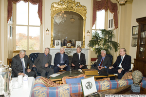 ["A group of six Senators sit together at a small event."]%