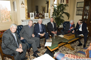 ["A group of six Senators sit together during a small event."]%