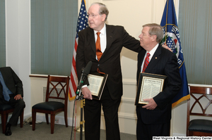 ["Senator John D. (Jay) Rockefeller and Senator John Isakson hold framed copies of a Congressional Record at an event in the Senate."]%