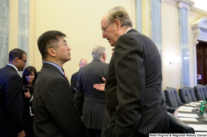 ["Senator John D. (Jay) Rockefeller speaking with an unidentified man in the Senate Commerce Committee hearing room."]%