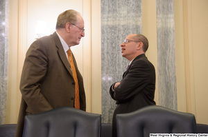 ["Senator John D. (Jay) Rockefeller speaks to an unidentified man before a Commerce Committee hearing."]%