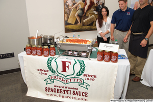 ["Three people stand behind a table for the Figaretti's Spaghetti Sauce company at the celebration for West Virginia's 150th birthday."]%