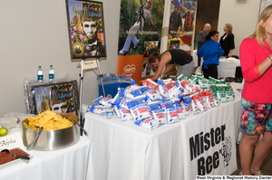 ["A woman stands before the Mister Bee table at the 150th birthday celebration for West Virginia."]%