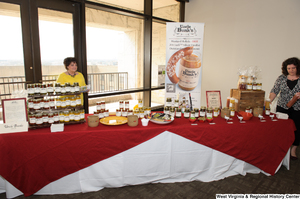 ["Two women stand by the Uncle Buck's table at the West Virginia 150th birthday celebration at the Senate."]%