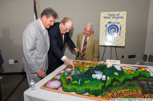 ["Senator John D. (Jay) Rockefeller cuts the West Virginia birthday cake during the state's 150th birthday celebration."]%