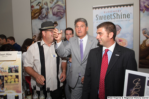 ["Senator Joe Manchin raises a sample of a West Virginia liquor."]%