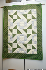 ["A green, blue, and white geometric quilt hangs in Senator John D. (Jay) Rockefeller's office."]%