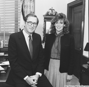 ["Senator John D. (Jay) Rockefeller sits on his desk and poses for a photograph with an unidentified individual."]%