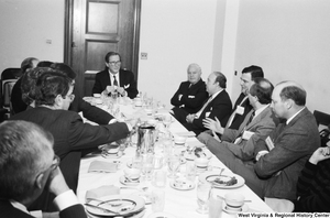 ["Senator John D. (Jay) Rockefeller listens to a man speak at a breakfast banquet in the Senate."]%