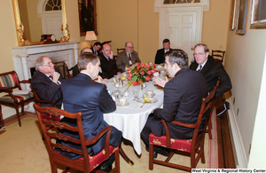 ["Senator John D. (Jay) Rockefeller sits with unidentified men at a luncheon."]%