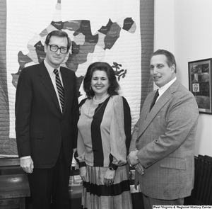 ["Senator John D. (Jay) Rockefeller poses for a photograph with a woman from the Department of Employment Security and a man from Elkins Iron in his Washington office."]%