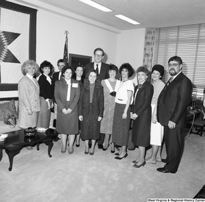 ["Senator John D. (Jay) Rockefeller stands for a photograph in his office with a large group of unidentified individuals."]%