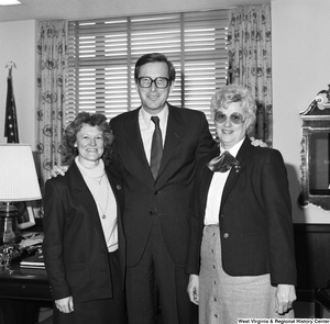 ["Senator John D. (Jay) Rockefeller stands for a photograph in his office with two unidentified women."]%
