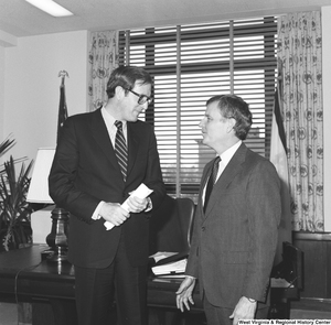 ["Senator John D. (Jay) Rockefeller holds a rolled up piece of paper as he speaks with FEMA Assistant Director Sam Speck in his Washington office."]%