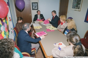 ["Senator John D. (Jay) Rockefeller sitting at the conference table in his office with a group of child care advocates."]%