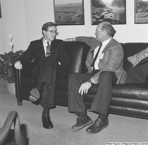 ["Senator John D. (Jay) Rockefeller sits on a couch next to an unidentified man."]%