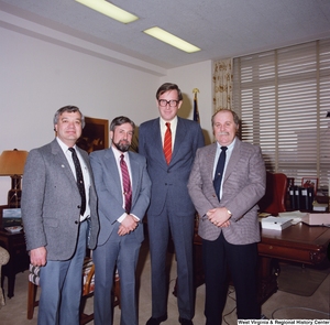 ["Senator John D. (Jay) Rockefeller stands for this color photograph in front of the desk in his office with three representatives from the West Virginia Homebuilders Association."]%