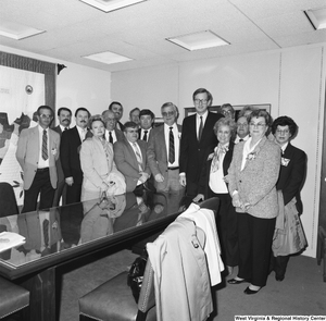 ["Senator John D. (Jay) Rockefeller stands with a large group around a conference table in his office."]%