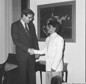 ["Senator John D. (Jay) Rockefeller shakes hands with an unidentified young man in his office."]%