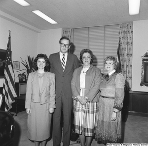 ["Senator John D. (Jay) Rockefeller stands for a photograph in front of his desk with three unidentified women."]%