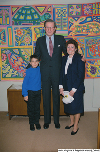 ["Senator John D. (Jay) Rockefeller stands in his office with a young boy and his mother."]%
