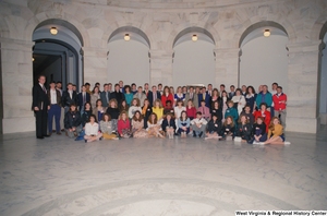 ["Senator John D. (Jay) Rockefeller stands beside a group of students in a rotunda at the U.S. Capitol Building."]%