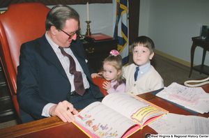 ["Senator John D. (Jay) Rockefeller signs a book for two young children."]%