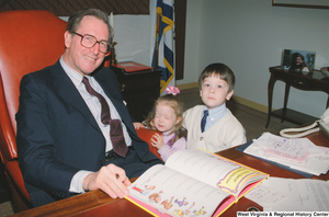 ["Senator John D. (Jay) Rockefeller smiles for a photograph with two small children."]%