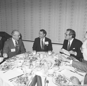 ["Senator John D. (Jay) Rockefeller sits at a dinner table with several unidentified individuals."]%